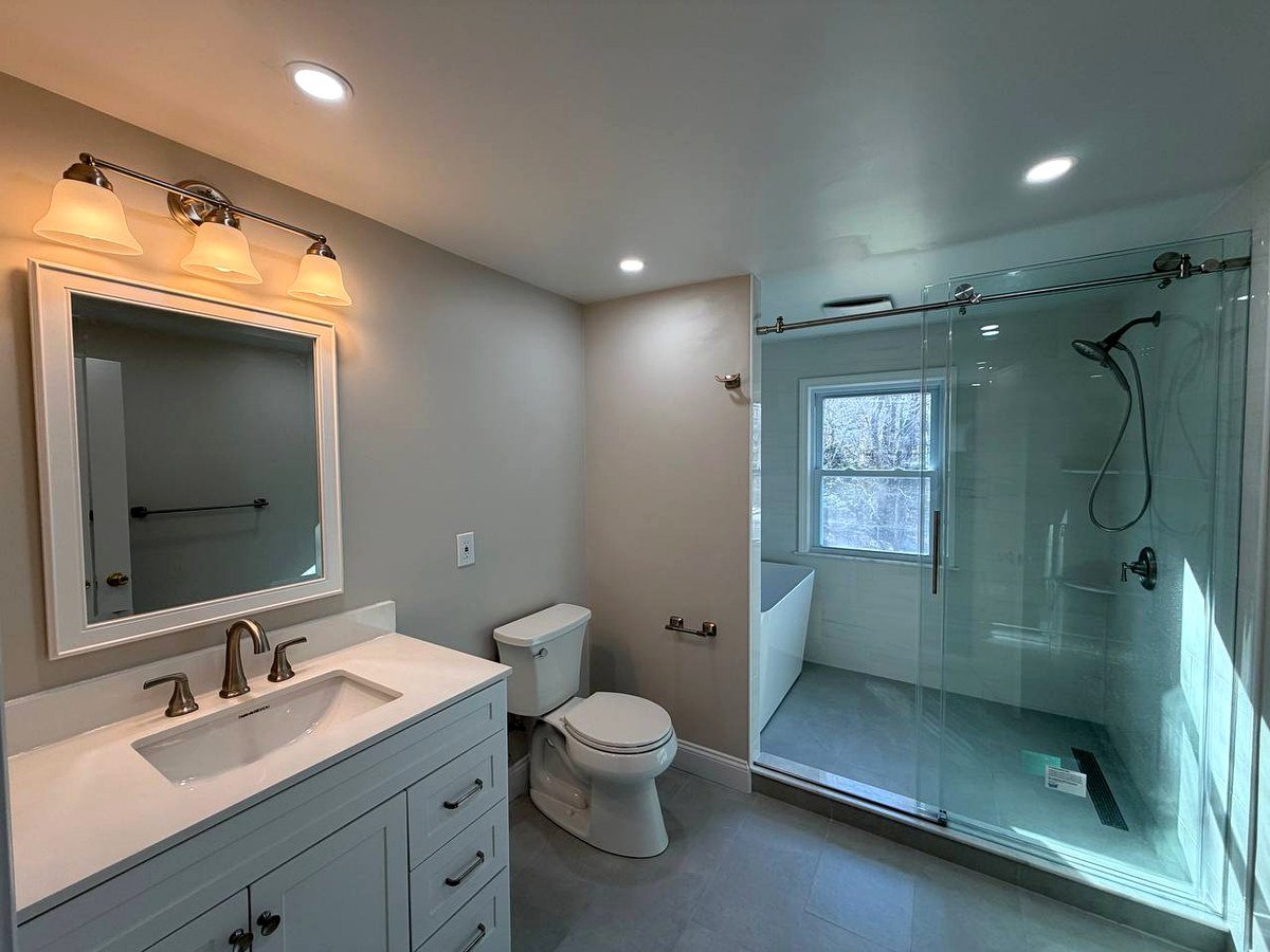 Bathroom renovation Lexington MA - master bath with walk-in shower, frameless glass door, white vanity and vanity lighting