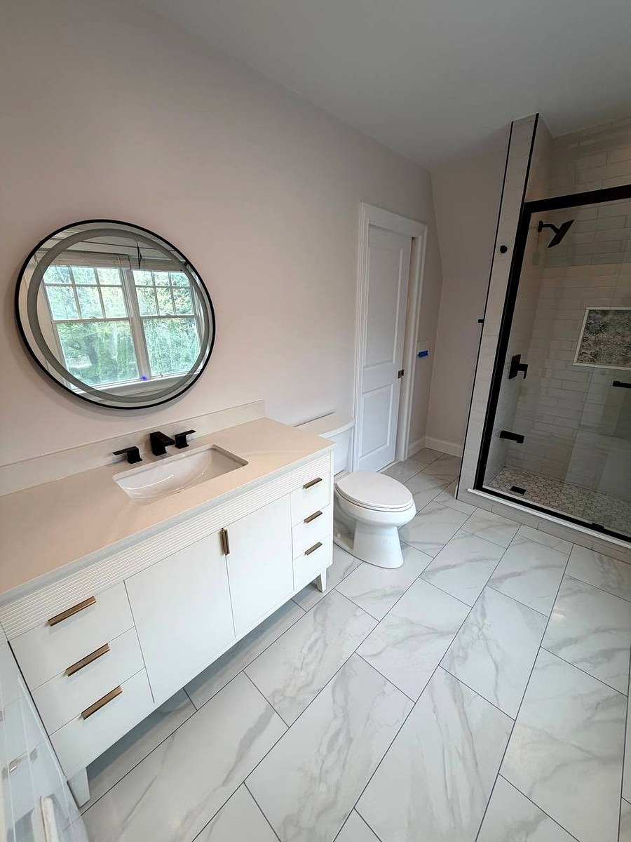 Bathroom renovation Newton Center MA - white vanity with round mirror and walk-in shower