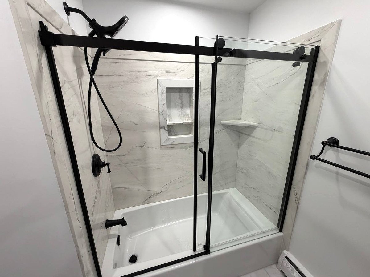 Bathroom remodel Norwood MA - marble look tile panels with built-in niche and black hardware