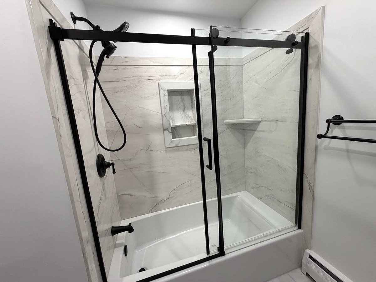 Bathroom renovation Norwood MA - full view of bathtub shower area with marble wall tiles