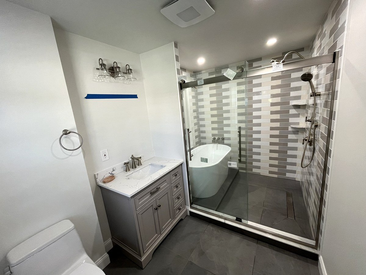 Bathroom renovation Watertown MA - full room overview with gray vanity, soaking tub in shower, and gray floor tile