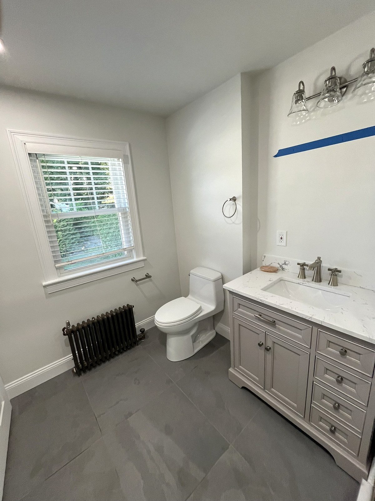 Bathroom renovation Watertown MA - gray vanity with window and restored cast iron radiator