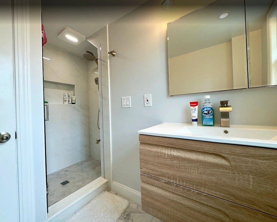 Bathroom renovation Wellesley MA - floating wood-look vanity with white sink and frameless glass walk-in shower