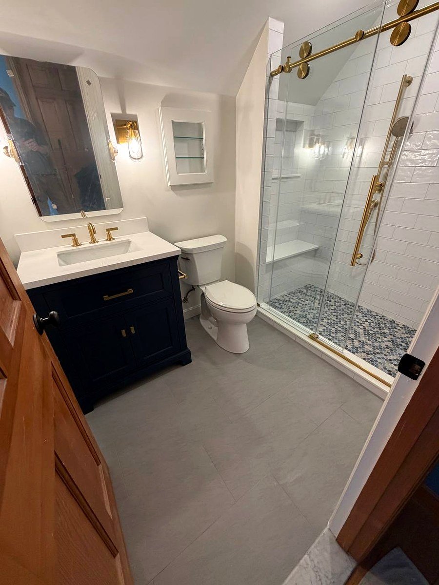 Bathroom renovation Westwood MA - navy blue vanity with gold fixtures and walk-in shower