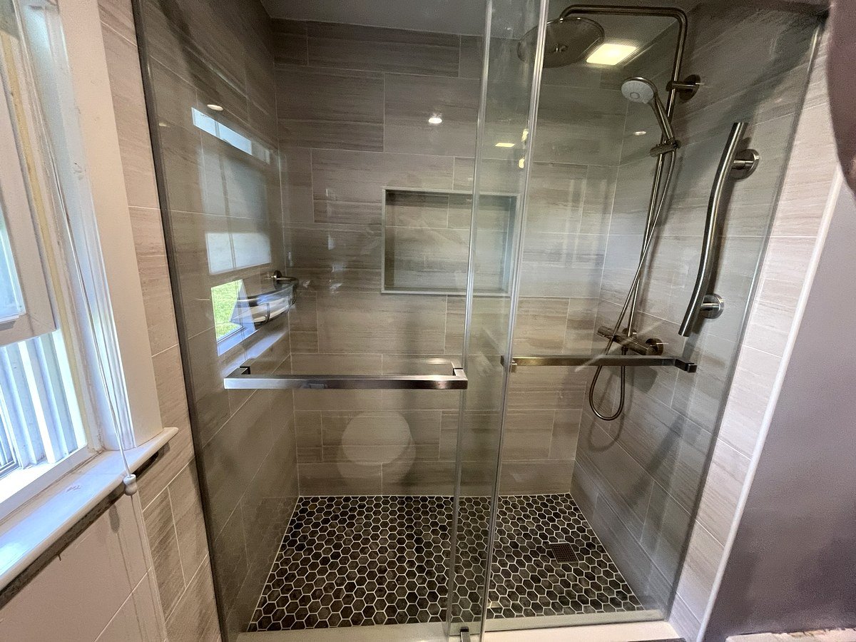 Walk-in shower renovation Braintree MA - frameless sliding glass door, gray stone-look wall tile, and dark hex mosaic floor
