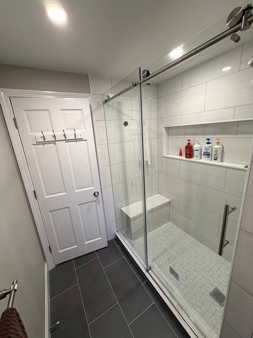 Walk-in shower renovation Milton MA - spa transformation with sliding glass door and white large-format tiles