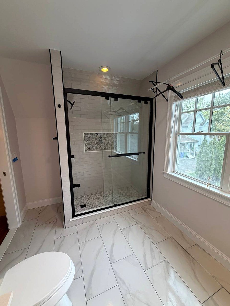 Walk-in shower renovation Newton Center MA - black frame sliding glass door with white wall tiles