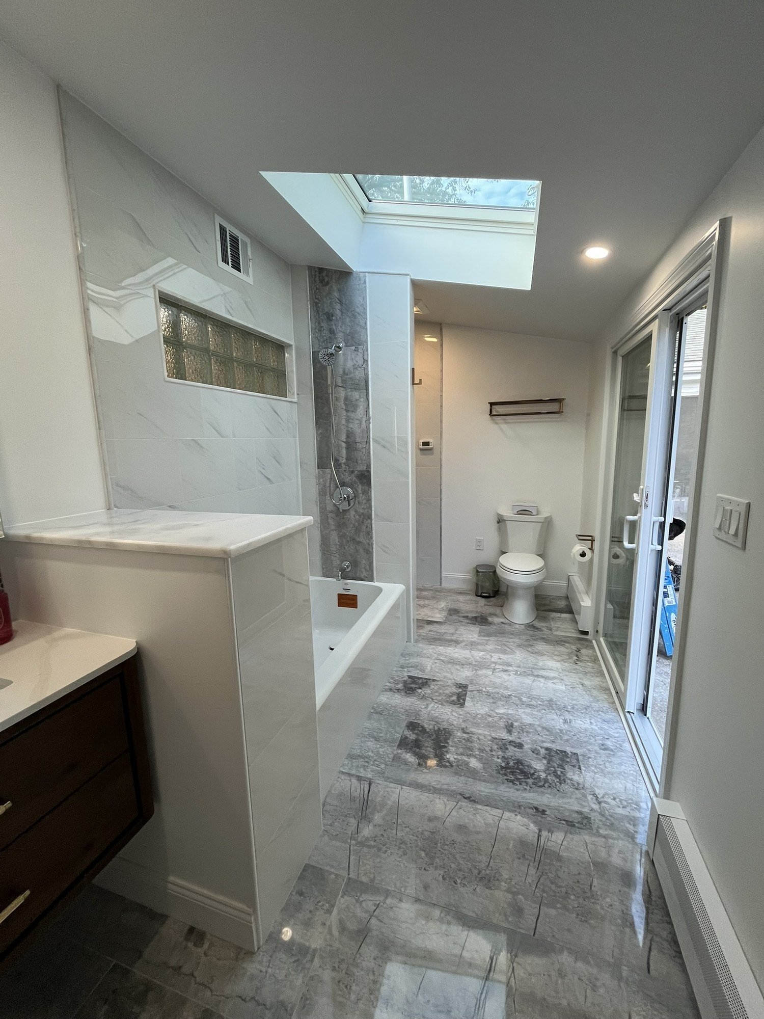 Second bathroom with skylight, tub and shower area and floating vanity